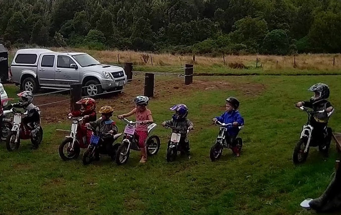 Kids line up on their electric motorcycles for a trials event.