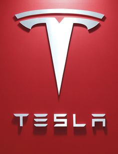 An attendee walks past the Tesla Motors Inc. logo displayed at the 43rd Tokyo Motor Show 2013 in Tokyo, Japan, on Thursday, Nov. 21, 2013. The autoshow will be open to the public from Nov. 23 to Dec. 1 at the Tokyo International Exhibition Center, also known as the Tokyo Big Sight. Photographer: Kiyoshi Ota/Bloomberg