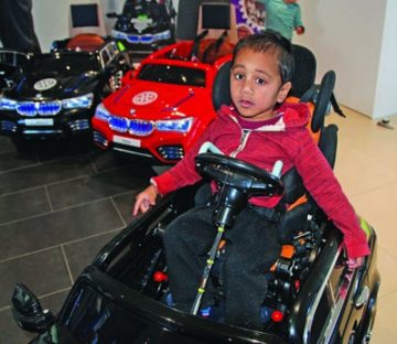 Three-year-old Ezekiel
can now drive
himself, thanks to an
adaptation which slots
his wheelchair seat into
his own electric BMW.
