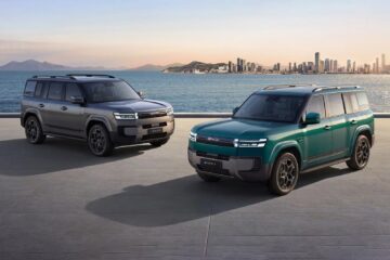Two BYD Ti 7 SUVs in grey and green by the coast