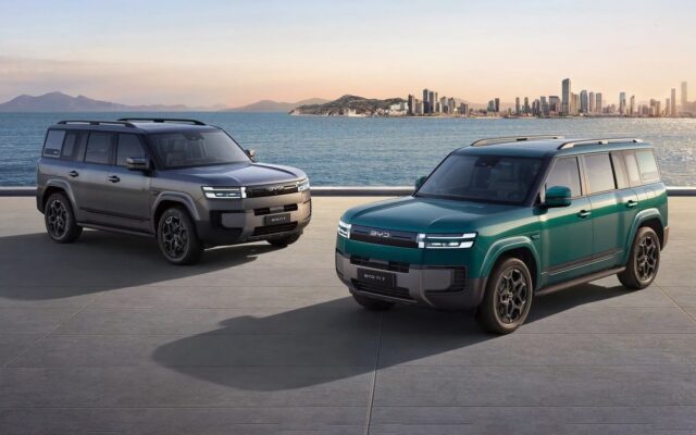Two BYD Ti 7 SUVs in grey and green by the coast