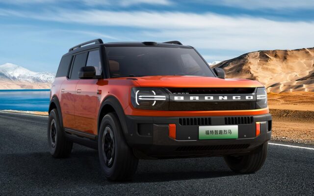 Orange Ford Bronco New Energy front three quarter on a mountain road