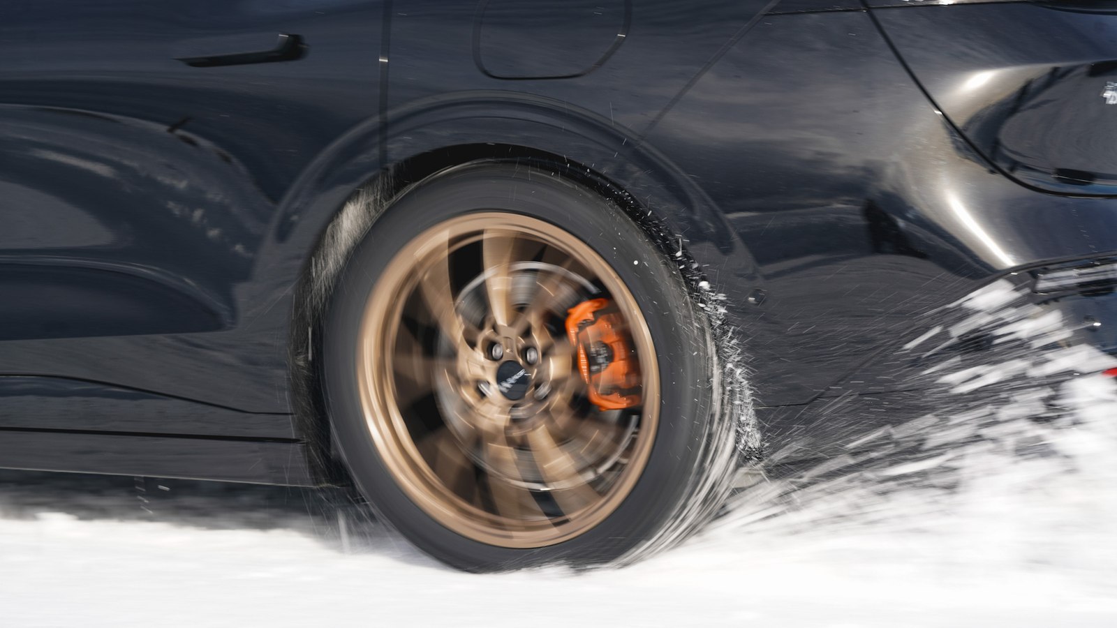 Close up of a Zeekr 7GT wheel with orange brake calipers in snow