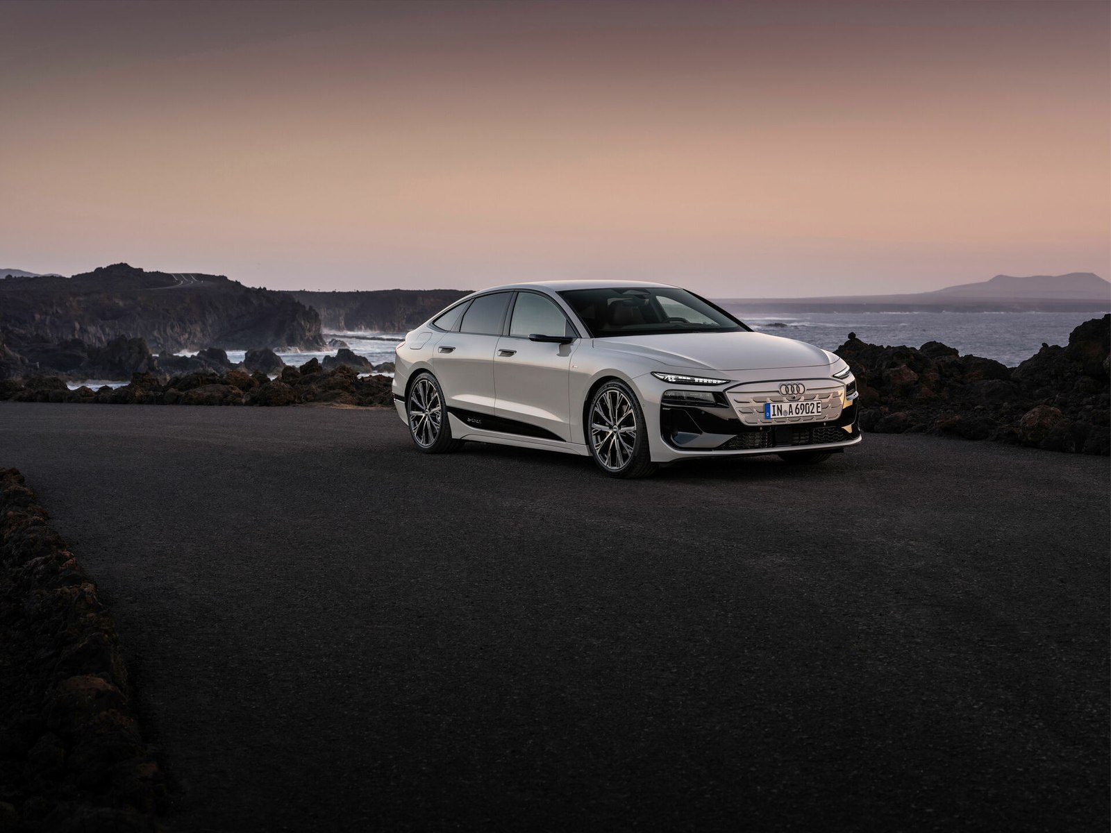 Silver Audi A6 Sportback e-tron parked on a coastal road at dusk