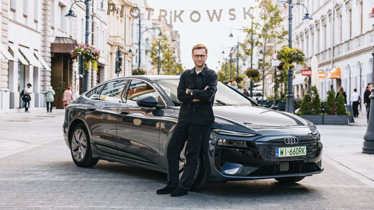 Miko Marczyk standing beside the black Audi A6 Sportback e-tron in a city street
