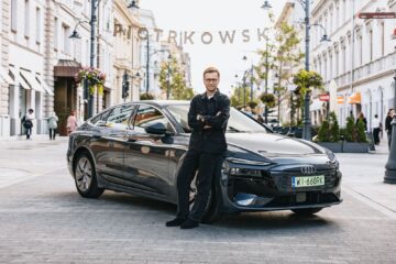Miko Marczyk standing beside the black Audi A6 Sportback e-tron in a city street