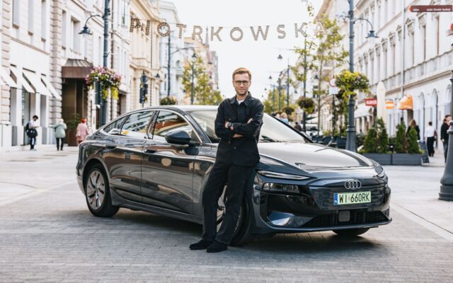 Miko Marczyk standing beside the black Audi A6 Sportback e-tron in a city street