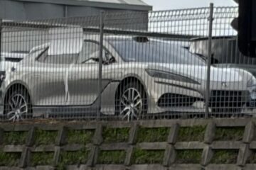 Silver Denza Z9GT behind a fence in an Auckland vehicle storage yard beside a Denza B8