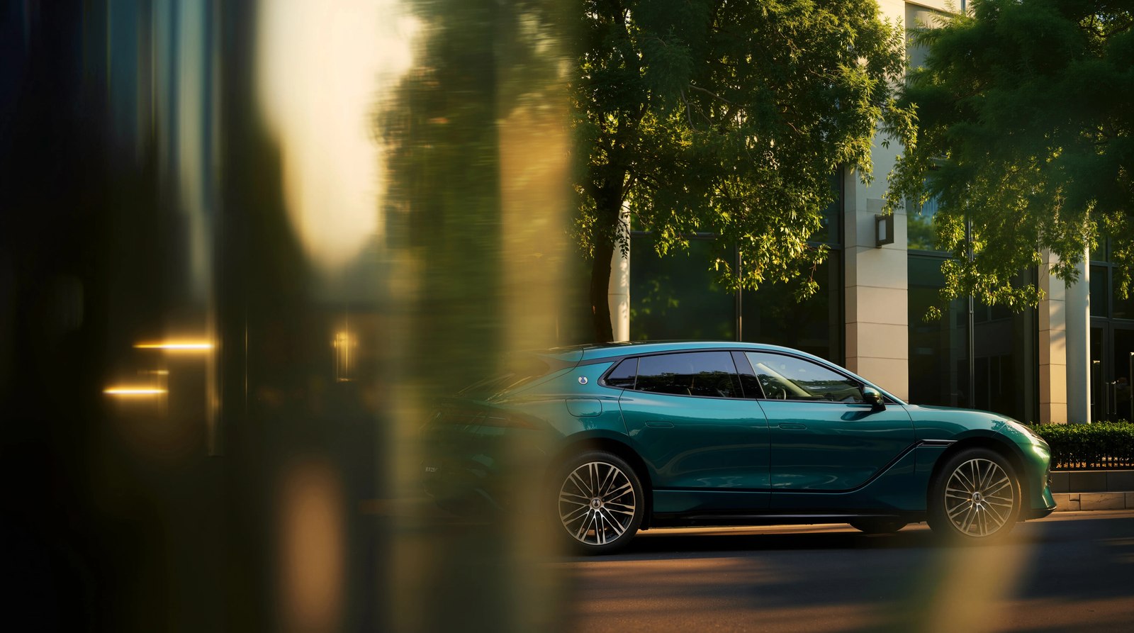 Teal Denza Z9GT shooting brake side profile beside a glass building