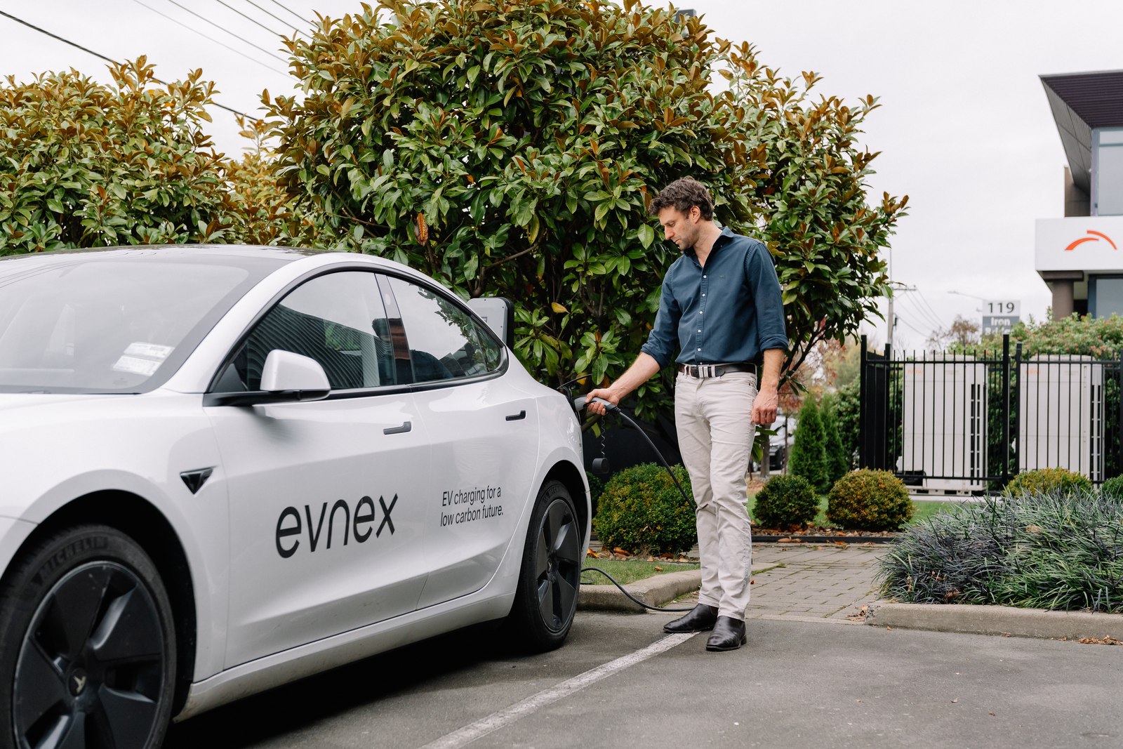 An Evnex charger being used on a car at a home driveway