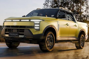 Yellow Nissan Frontier Pro PHEV front three quarter driving on a wet road