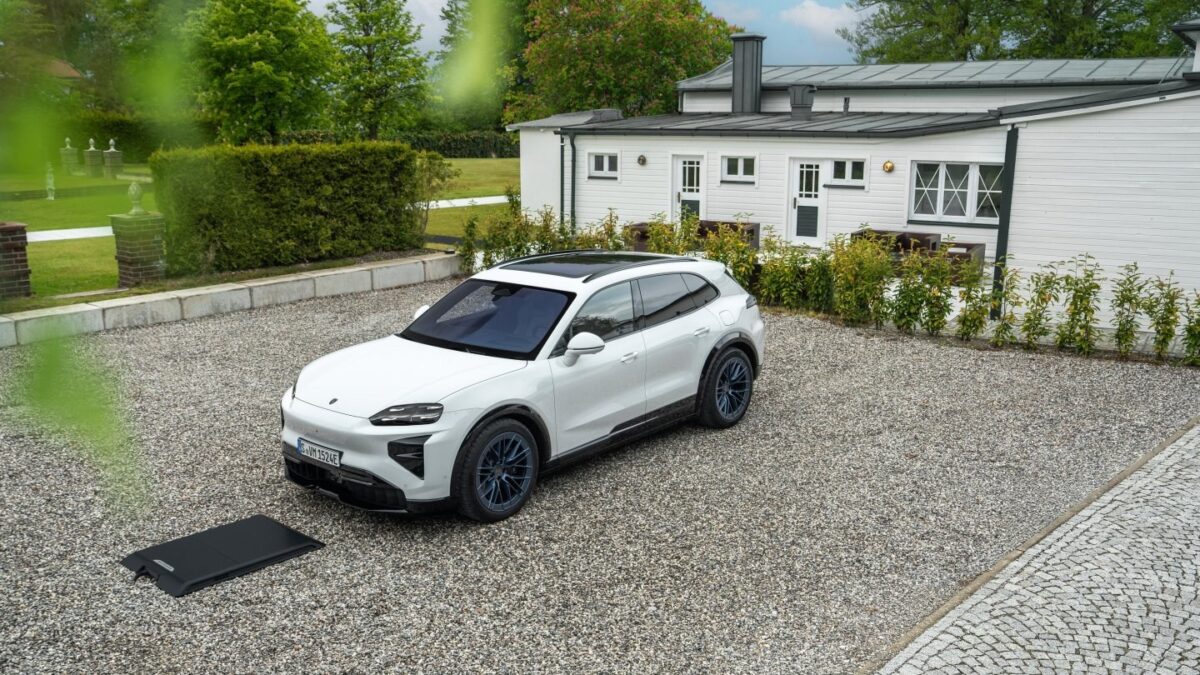 White Porsche Cayenne Electric parked beside a wireless charging ground pad on gravel