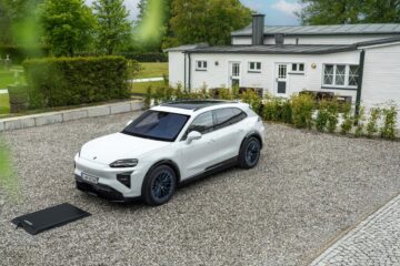 White Porsche Cayenne Electric parked beside a wireless charging ground pad on gravel