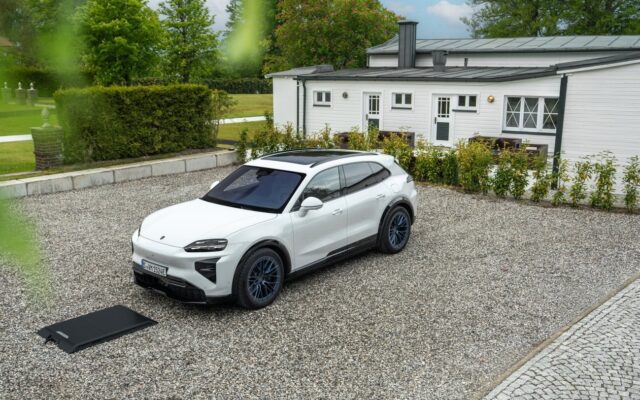 White Porsche Cayenne Electric parked beside a wireless charging ground pad on gravel