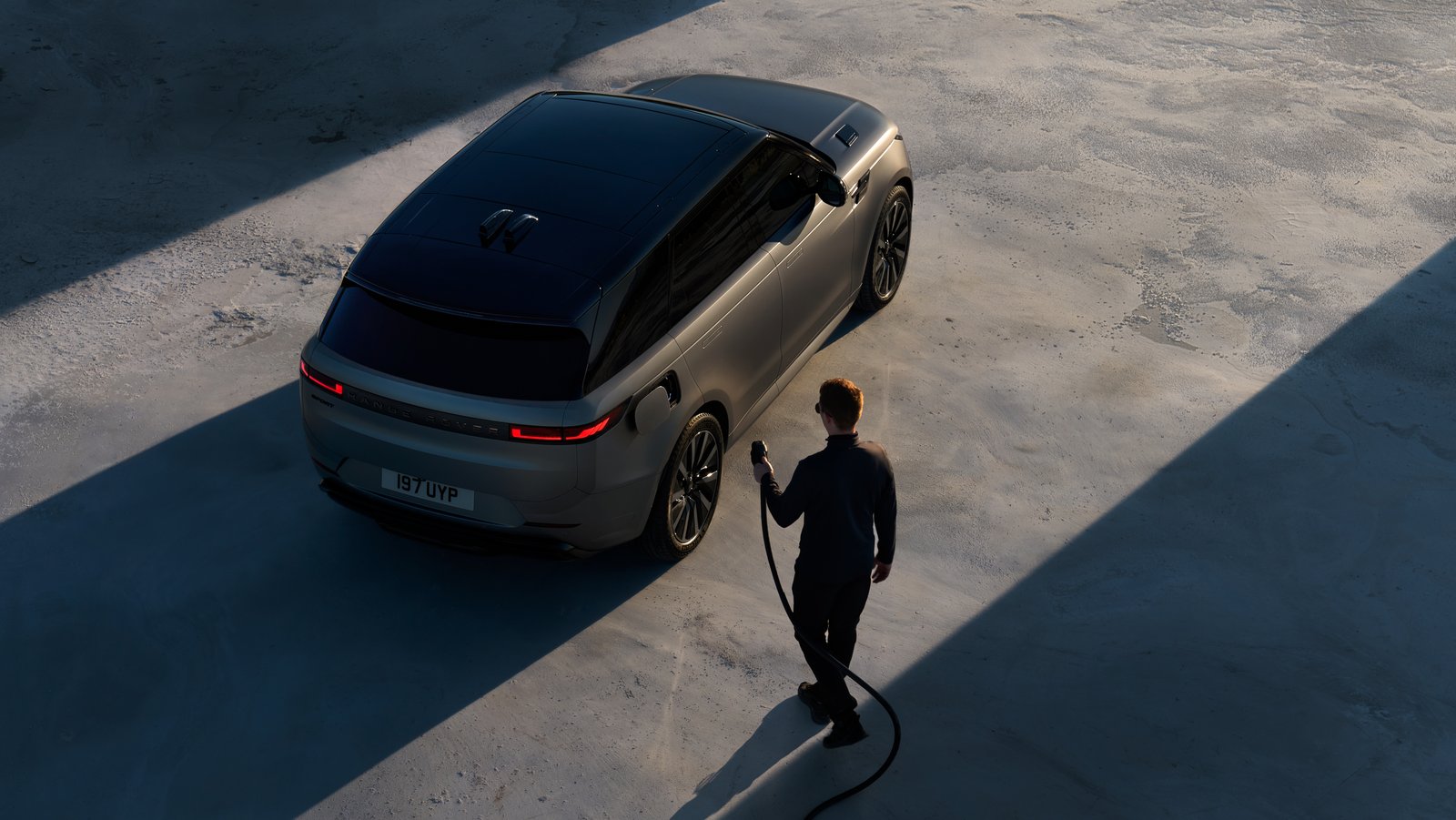 Overhead view of a grey Range Rover Sport Electric being plugged in to charge