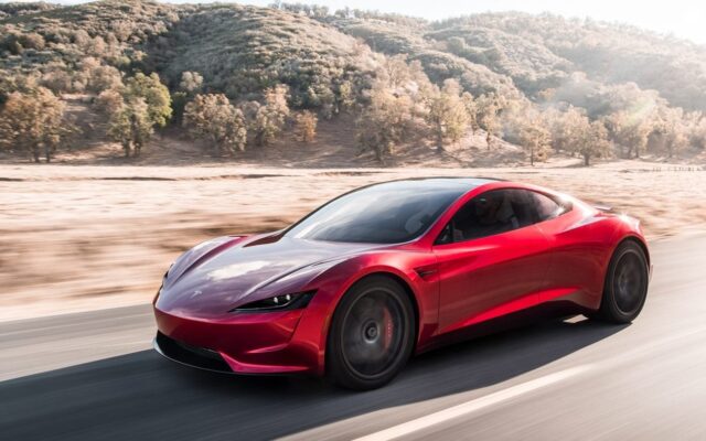 Red Tesla Roadster prototype driving on a desert road