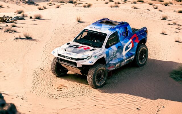 Toyota DKR GR FC Hilux hydrogen rally truck driving through sand dunes