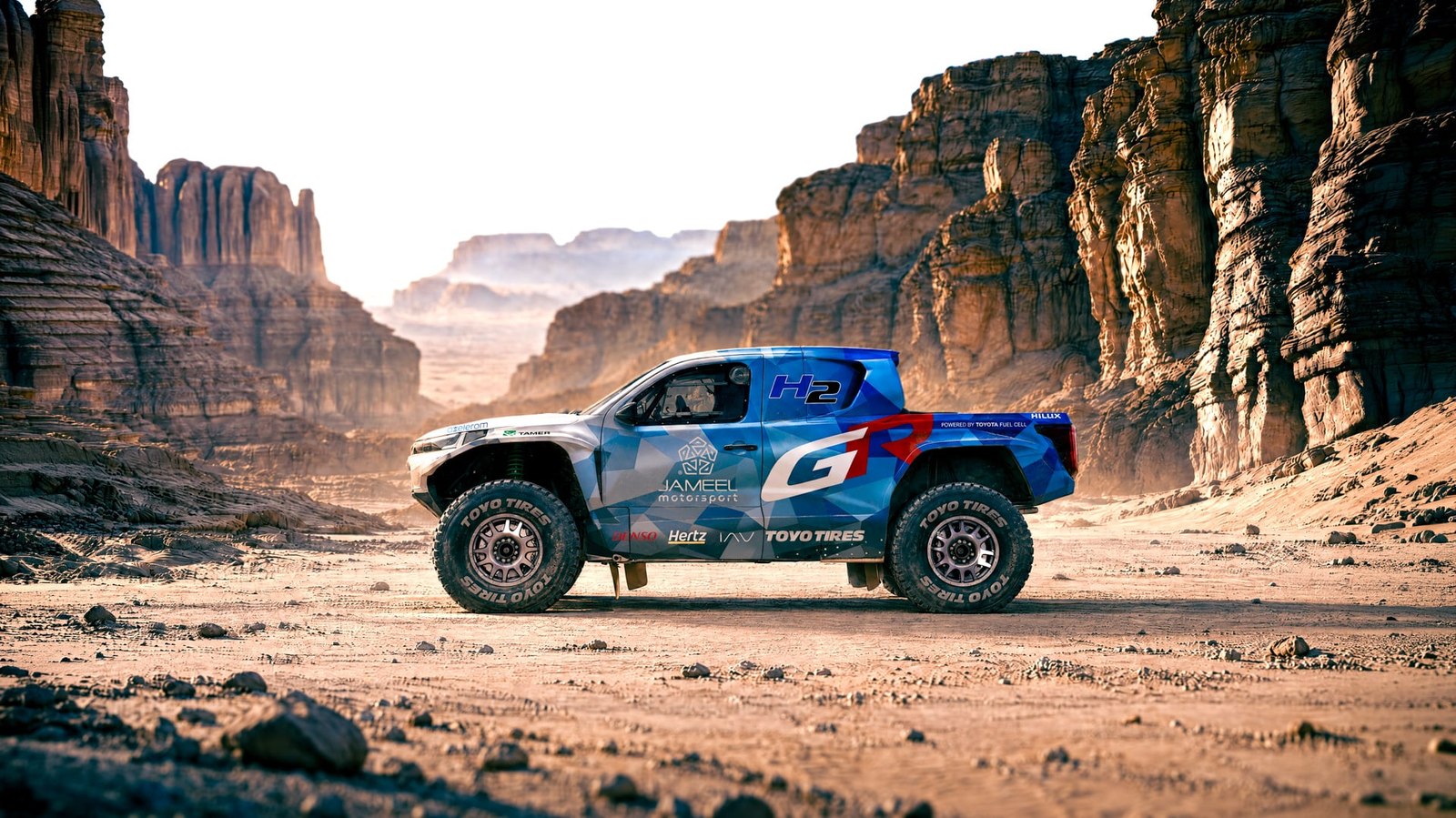 Toyota DKR GR FC Hilux hydrogen rally truck side view in a desert canyon