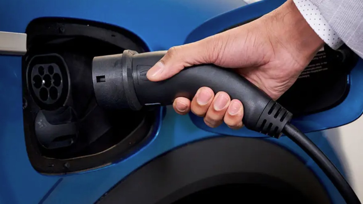 Hand plugging a charging connector into an electric car