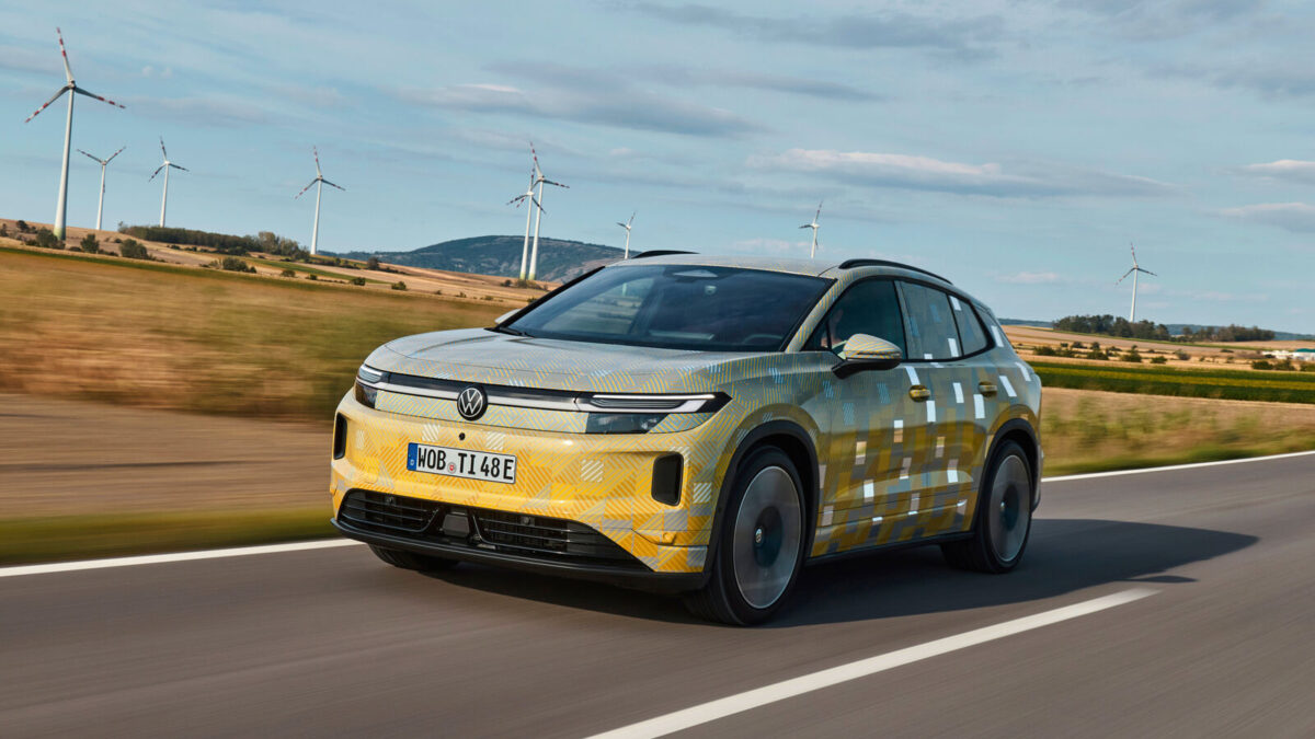 Camouflaged Volkswagen ID. Tiguan prototype driving past wind turbines