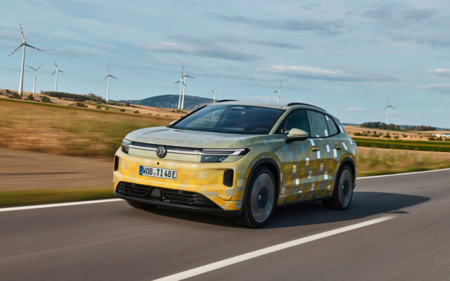 Camouflaged Volkswagen ID. Tiguan prototype driving past wind turbines