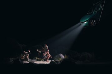 Caveman scene from Taika Waititi's Spotlight exhibition, lit by the headlights of a Zeekr 7X
