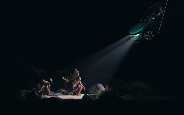 Caveman scene from Taika Waititi's Spotlight exhibition, lit by the headlights of a Zeekr 7X