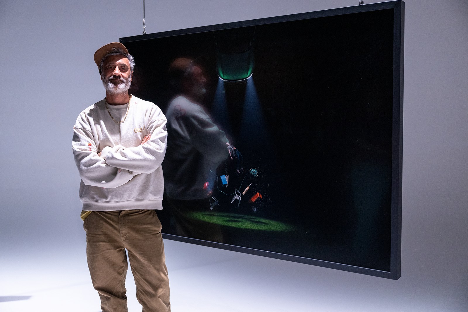 Taika Waititi standing beside a large framed image from the Spotlight exhibition