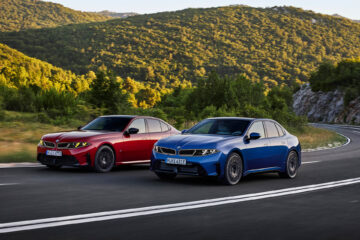 Blue BMW i3 and red BMW 3 Series sedans on a mountain road
