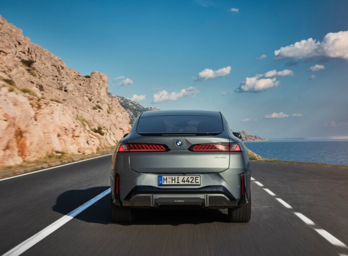 BMW iX4 rear view on a coastal road