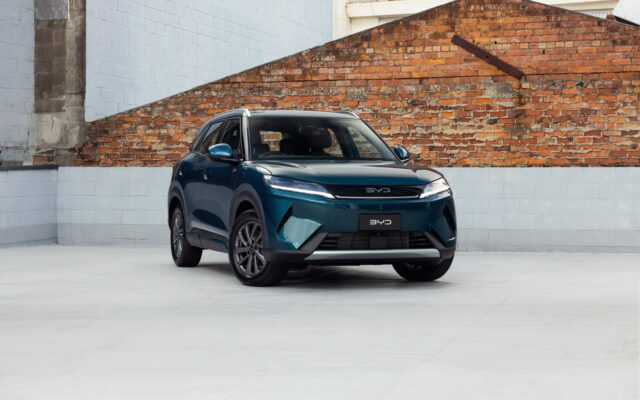 Teal BYD Atto 2 DM-i parked in front of a brick wall