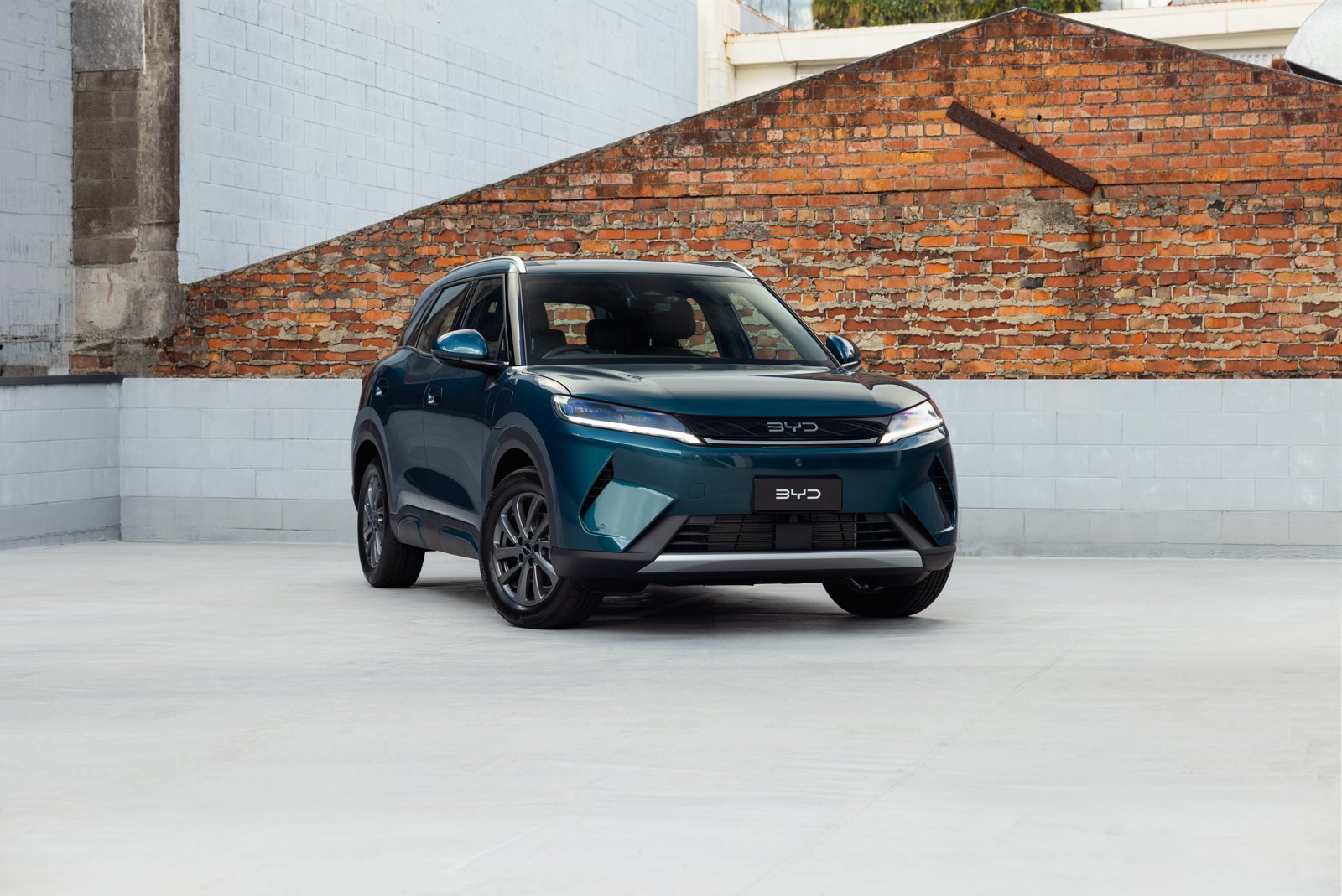 Teal BYD Atto 2 DM-i parked in front of a brick wall