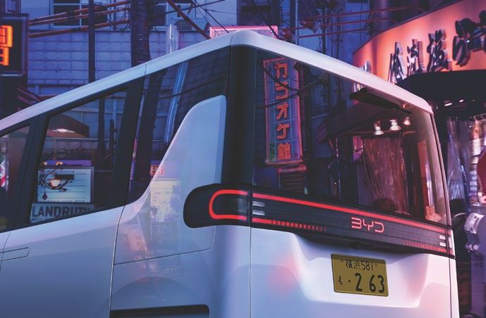 BYD Racco kei car rear three-quarter under neon signs in Tokyo