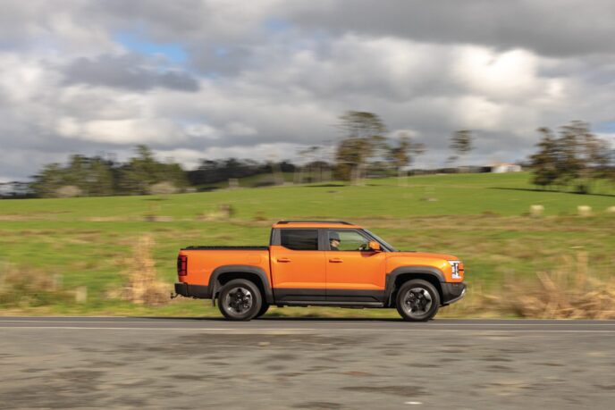 Orange BYD Shark 6 ute driving past farmland