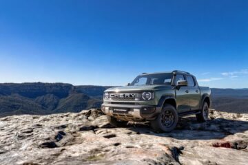 Green Chery Stockman ute parked on a rock ledge above a valley