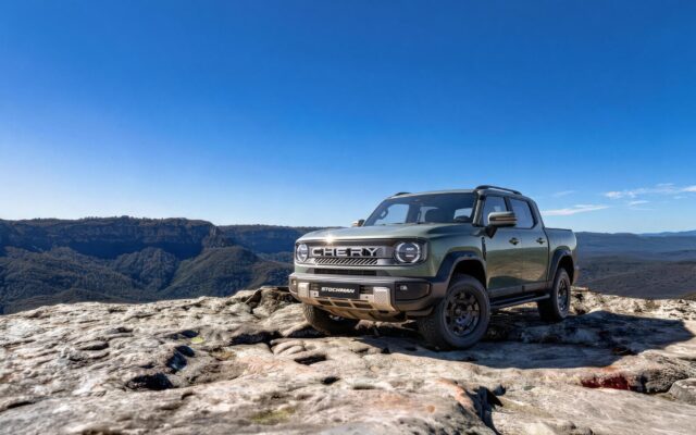 Green Chery Stockman ute parked on a rock ledge above a valley