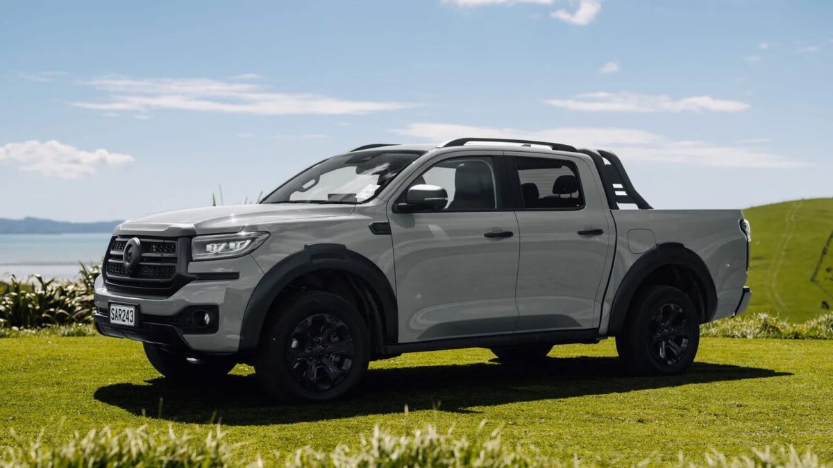 Red GWM Cannon Hi4-T PHEV ute front three-quarter view on a farm track