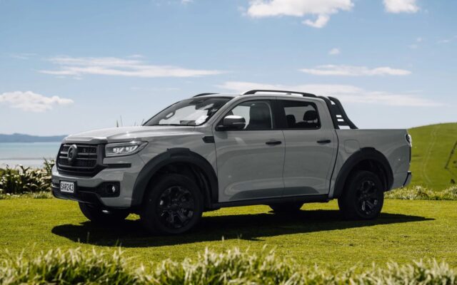 Red GWM Cannon Hi4-T PHEV ute front three-quarter view on a farm track