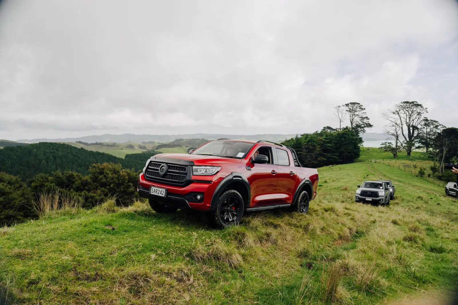 Red GWM Cannon Hi4-T PHEV on a farm hillside