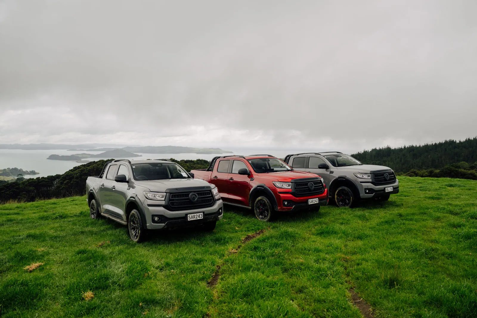 Three GWM Cannon Hi4-T PHEV utes parked on a coastal hilltop
