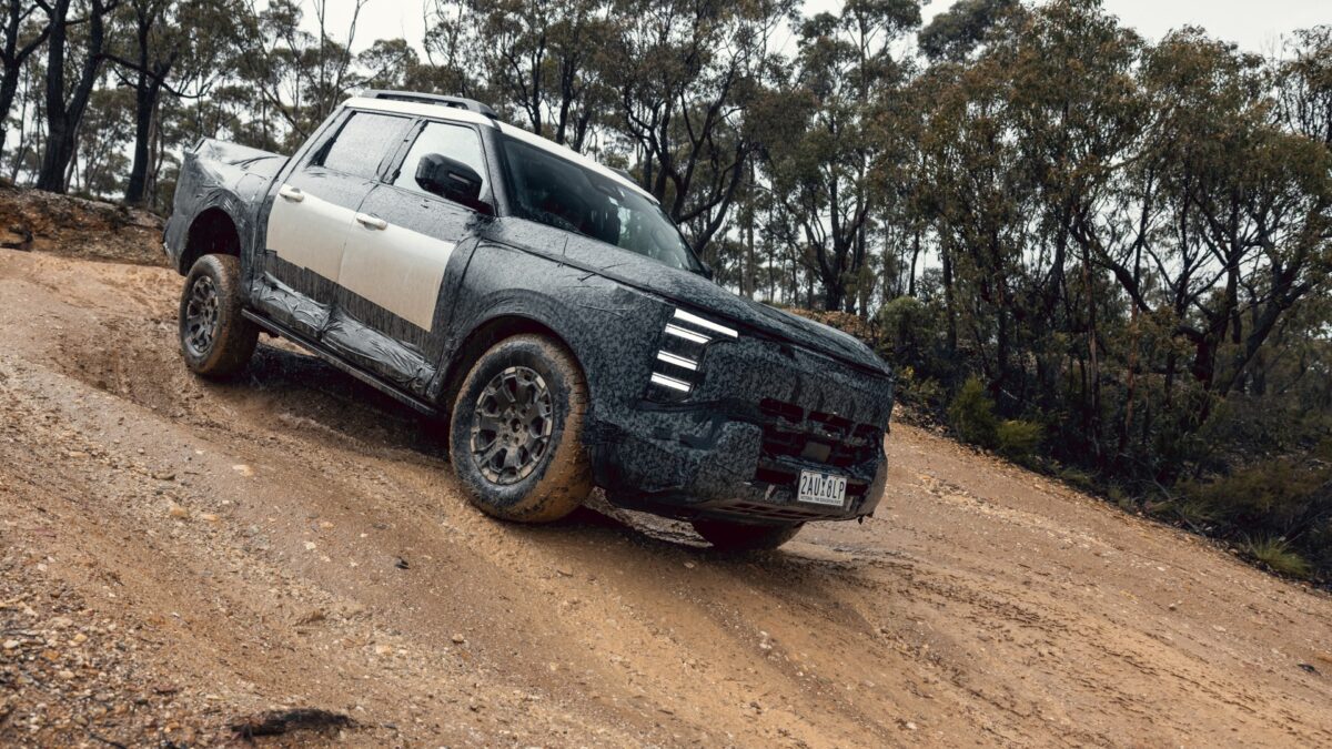 Camouflaged Nissan Navara Pro PHEV prototype climbing a dirt track