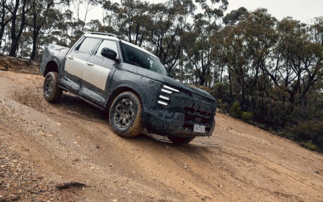 Camouflaged Nissan Navara Pro PHEV prototype climbing a dirt track