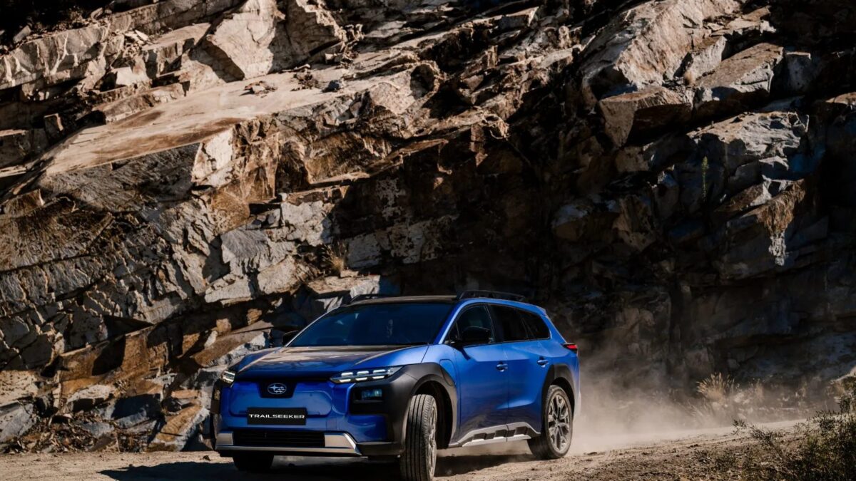 Blue Subaru Trailseeker AWD Touring driving past a rock face on a dusty road