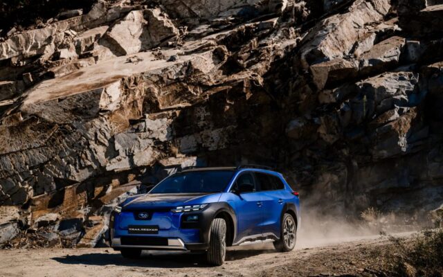Blue Subaru Trailseeker AWD Touring driving past a rock face on a dusty road