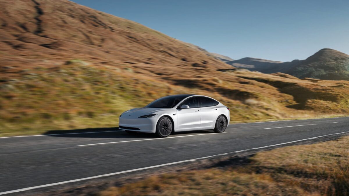 Tesla Model 3 driving through dry hills