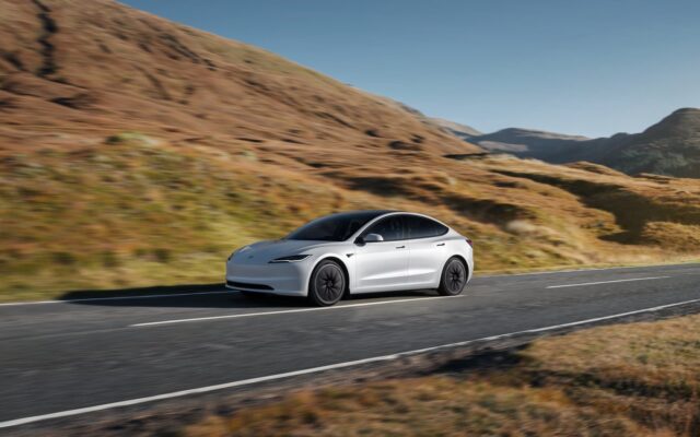 Tesla Model 3 driving through dry hills