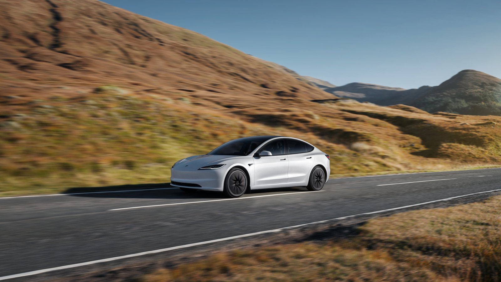 Tesla Model 3 driving through dry hills