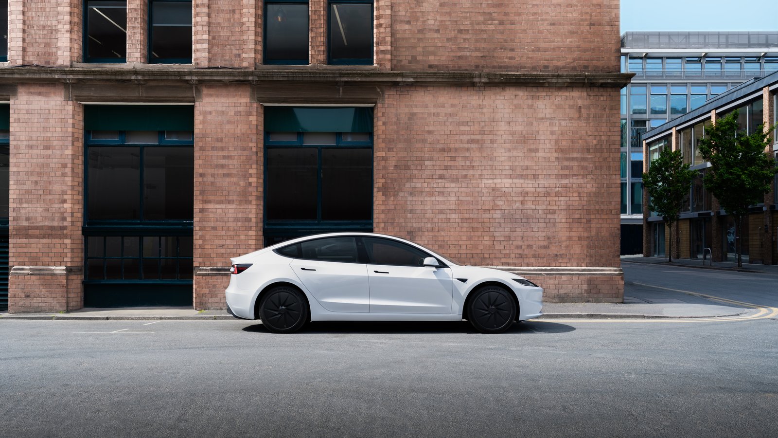 White Tesla Model 3 parked in front of a brick building