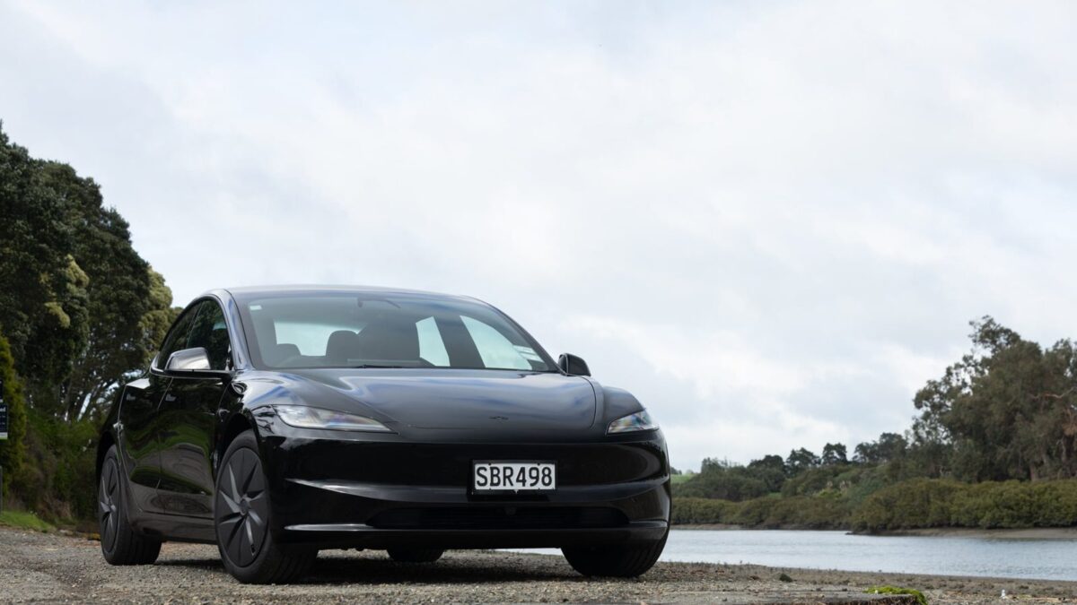 Black Tesla Model 3 Rear-Wheel Drive parked beside an estuary
