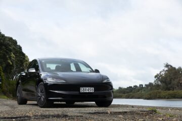 Black Tesla Model 3 Rear-Wheel Drive parked beside an estuary